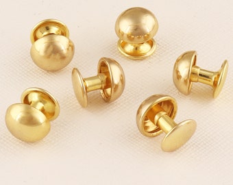 May include: Six gold-toned metal dome-shaped studs with a flat back. The studs have a smooth, shiny finish.