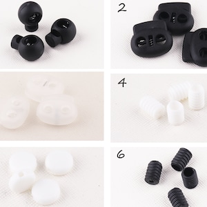 May include: Assortment of black and white plastic toggle clasps and stoppers.  The clasps have two holes and the stoppers have a spring mechanism.  The clasps and stoppers are used for securing cords, straps, and other items.