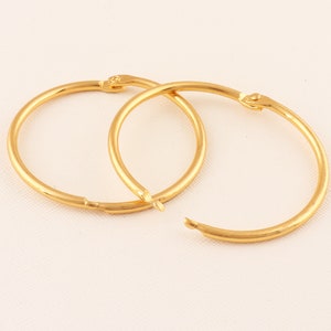 May include: A pair of gold hoop earrings. The earrings are simple and classic, with a smooth finish.
