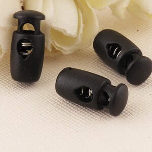 Puede incluir: Tres cierres de cordón de plástico negro con un mecanismo de resorte. Los cierres de cordón están diseñados para asegurar cordones o correas.