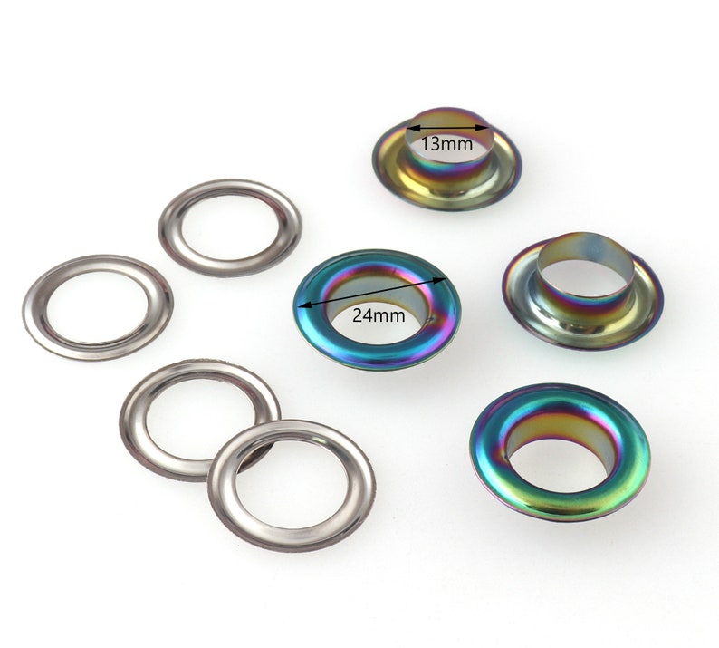 Op de afbeelding: Assortiment van metalen oogjes in verschillende maten, waaronder 13 mm en 24 mm. De oogjes hebben een regenboogkleurige, iriserende afwerking.