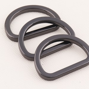 May include: Three black metal D-rings of different sizes.