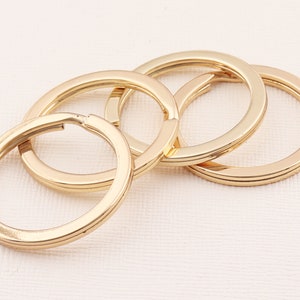 May include: Four gold-coloured metal key rings of different sizes, interlocked together.