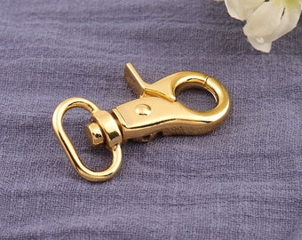 May include: A gold-toned metal swivel clasp with a D-ring. The clasp is designed to attach to a leash, strap, or other item.