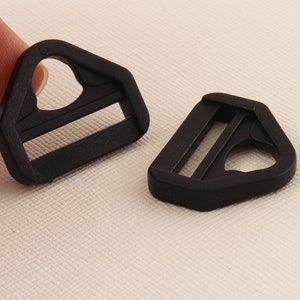 May include: Two black plastic slider buckles. The buckles are triangular in shape with a rectangular opening in the center.