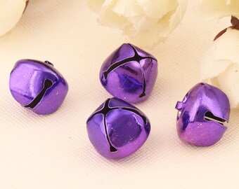 May include: Four purple metal jingle bells with a shiny finish. The bells are round and have a small opening at the top for attaching to a string or ribbon.
