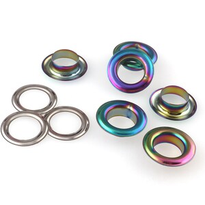 Op de afbeelding: Assortiment van iriserende metalen oogjes in verschillende maten. De oogjes hebben een glanzende, regenboogachtige afwerking.