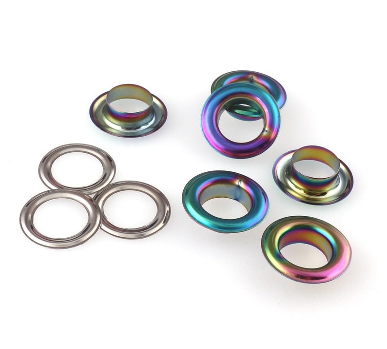 Op de afbeelding: Assortiment van iriserende metalen oogjes in verschillende maten. De oogjes hebben een glanzende, regenboogachtige afwerking.