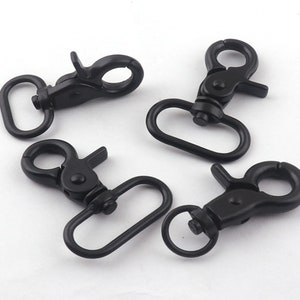 Könnte beinhalten: Vier schwarze Metall-Schwenkverschlüsse mit einem D-Ring. Die Verschlüsse sind zum Befestigen an Taschen, Gurten oder anderem Zubehör gedacht.