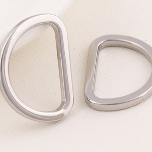May include: Two silver metal D-rings, each with a smooth, rounded edge. The rings are about 2 inches in diameter.