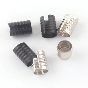 May include: Six metal cord ends, three are silver and three are black. The cord ends have a ribbed design and a split opening.