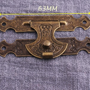 May include: Antique brass latch with ornate design, measuring 63mm in length. The latch has a decorative knob and a hinged design.
