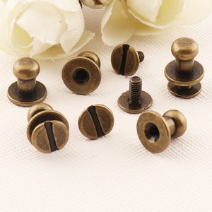 May include: A collection of eight antique brass-toned metal push buttons with a screw-on design. The buttons have a round base and a raised dome top.