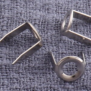 May include: Three silver metal eyelets with a round hole in the center. The eyelets are designed for use in fabric or leather.