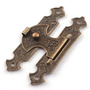 May include: Antique brass latch with ornate details and a decorative knob. The latch is designed to be used on a cabinet or door.