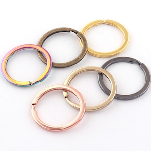 May include: Assortment of six key rings in different colors and finishes, including gold, silver, black, and rainbow.