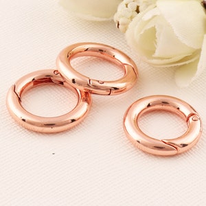 以下が含まれることがあります： 回転式留め具が付いた、ローズゴールドの金属製のキーリングが3つ。キーリングはサイズが異なります。