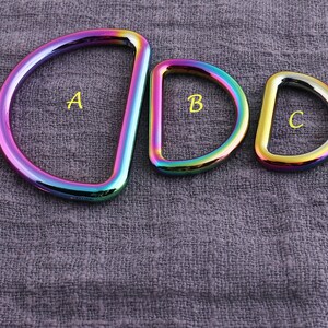 May include: Three rainbow-colored metal D-rings of different sizes. The largest ring is labeled "A", the middle ring is labeled "B", and the smallest ring is labeled "C".