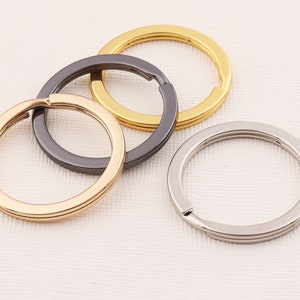 May include: Three key rings in different finishes: gold, silver, and black. The key rings are all made of metal and have a simple, circular design.