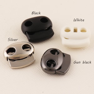 Puede incluir: Cuatro cierres de cordón de palanca en diferentes colores: negro, blanco, plateado y gris oscuro. Cada cierre tiene dos agujeros para cordones.