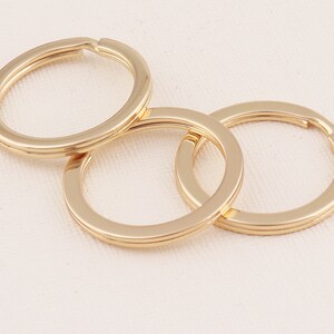 May include: Three gold-colored metal key rings, interlocked together. The key rings are smooth and shiny.