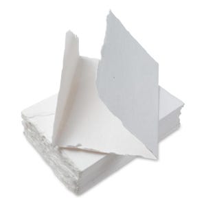 Puede incluir: Una pila de hojas de papel blanco hechas a mano con una sola hoja doblada y colocada en la parte superior. El papel tiene un aspecto texturizado y hecho a mano.