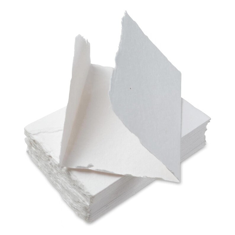Puede incluir: Una pila de hojas de papel blanco hechas a mano con una sola hoja doblada y colocada en la parte superior. El papel tiene un aspecto texturizado y hecho a mano.