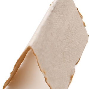 K&ouml;nnte beinhalten: Ein St&uuml;ck Pergamentpapier mit leicht rauer Textur und hellbrauner Farbe. Das Papier ist dreieckig gefaltet, die Kanten sind leicht ausgefranst.