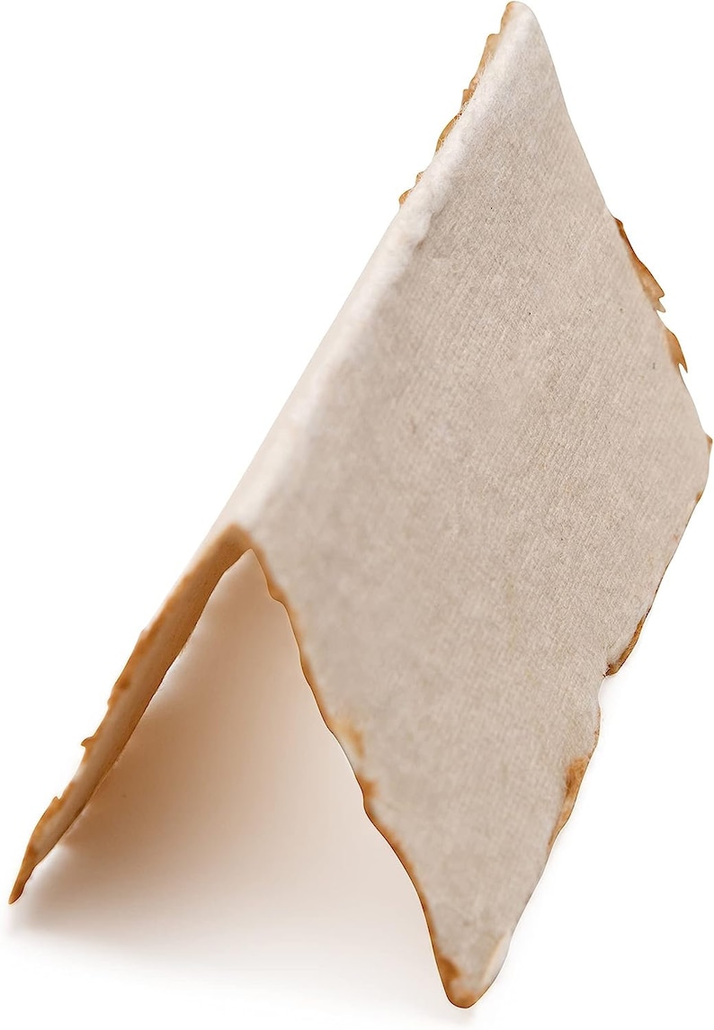 K&ouml;nnte beinhalten: Ein St&uuml;ck Pergamentpapier mit leicht rauer Textur und hellbrauner Farbe. Das Papier ist dreieckig gefaltet, die Kanten sind leicht ausgefranst.