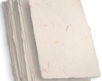 May include: A stack of white handmade paper sheets with a rough texture and flecks of natural fibers.