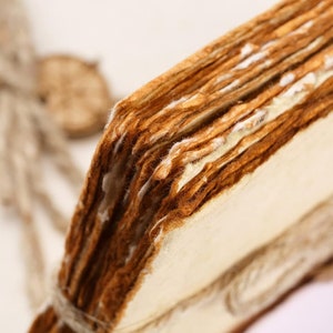 K&ouml;nnte beinhalten: Nahaufnahme eines Stapels alter, abgenutzter und vergilbter Papierseiten, die mit Schnur zusammengebunden sind. Die Seiten sind dicht gepackt und zeigen Spuren von Alter und Gebrauch.
