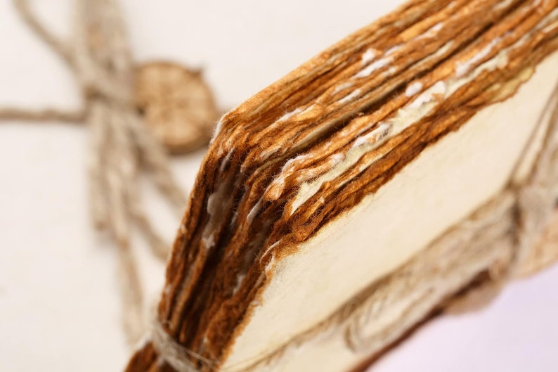 K&ouml;nnte beinhalten: Nahaufnahme eines Stapels alter, abgenutzter und vergilbter Papierseiten, die mit Schnur zusammengebunden sind. Die Seiten sind dicht gepackt und zeigen Spuren von Alter und Gebrauch.