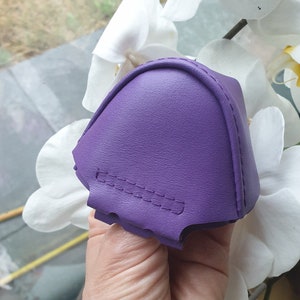 Puede incluir: Un calzador de cuero morado con una costura. El calzador se sostiene en una mano.