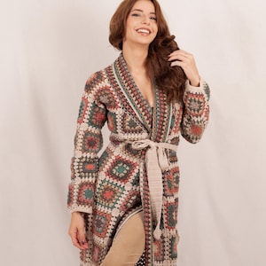 Può includere: Una tazza di ceramica bianca con manico nero e la scritta "But First, Coffee" in grassetto nero. La tazza è posta su uno sfondo sfocato, che suggerisce un'atmosfera accogliente.