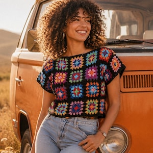 May include: A short-sleeved crochet top featuring a black base with a repeating pattern of multi-colored granny squares in shades of red, blue, yellow, purple, and pink, paired with light blue denim jeans.