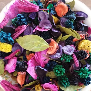 May include: A bowl filled with colourful potpourri, including dried flowers, leaves, and other natural elements. The potpourri features shades of pink, purple, green, yellow, and orange.