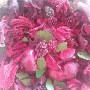 May include: A close-up of a mix of dried flowers and leaves in shades of pink, purple, and green. The flowers are arranged in a bowl and are a popular choice for potpourri.