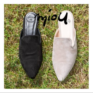 Puede incluir: Dos pares de zapatos de gamuza con punta puntiaguda. Un par es negro y el otro par es gris claro.