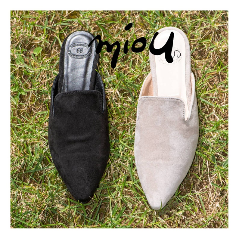 Puede incluir: Dos pares de zapatos de gamuza con punta puntiaguda. Un par es negro y el otro par es gris claro.