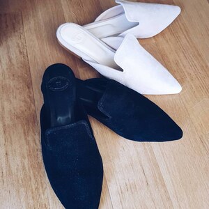 Puede incluir: Dos pares de zapatos de vestir de punta estrecha. Un par es de ante negro y el otro par es de ante blanco roto.