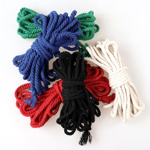 May include: Five spools of rope in different colours: green, blue, black, red, and white. The spools are arranged in a pile on a white background.