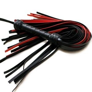 Puede incluir: Un l&aacute;tigo de cuero negro y rojo con un mango trenzado. El l&aacute;tigo tiene m&uacute;ltiples hebras de cuero que est&aacute;n atadas juntas en el extremo.