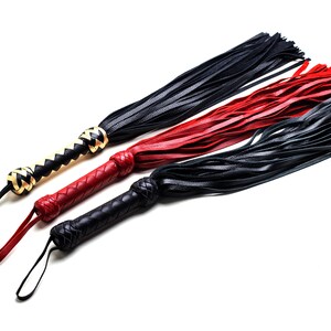May include: Three leather whips in black, red, and black. The handles are braided, with a loop at the end. One handle is black and tan, the other two are red and black. The whips have long, thin leather strands.