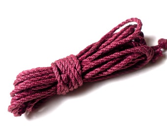 May include: A coil of thick, maroon-colored rope, tied in a knot at the center.