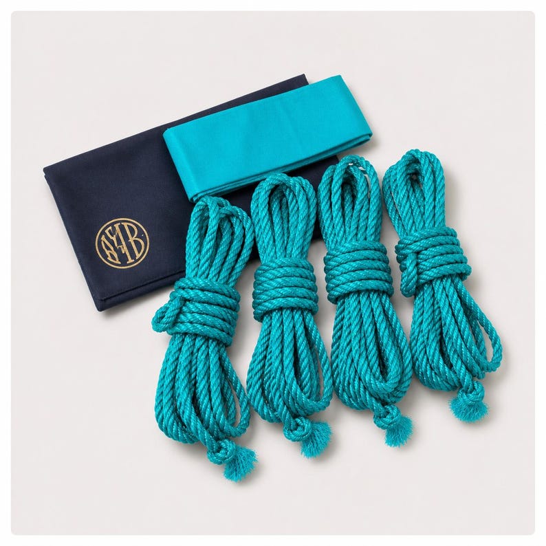 May include: Four coils of bright turquoise rope arranged in a row, accompanied by a folded turquoise fabric band and a dark navy blue rectangular fabric pouch featuring a circular gold logo with the letters AYB printed on the front surface.