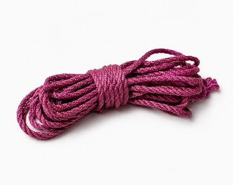 May include: A coiled length of deep magenta cord featuring a tightly twisted, multi-strand construction. The rope is wound into a compact, elongated bundle with a smooth, uniform texture and a consistent, vibrant dark pink color throughout.