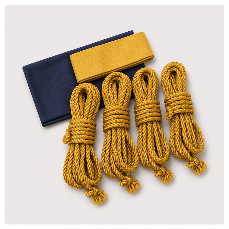 May include: A set of four mustard yellow coiled ropes arranged in a row, accompanied by a folded rectangular piece of dark navy blue fabric and a single folded strip of mustard yellow fabric positioned on top of the navy blue cloth.