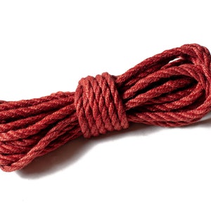 May include: A close-up of a red rope coiled and tied into a knot. The rope is made of a soft, textured material.