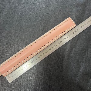 May include: A pink leather strap with a decorative stitch pattern. The strap is measured with a ruler, showing a length of 37 inches.
