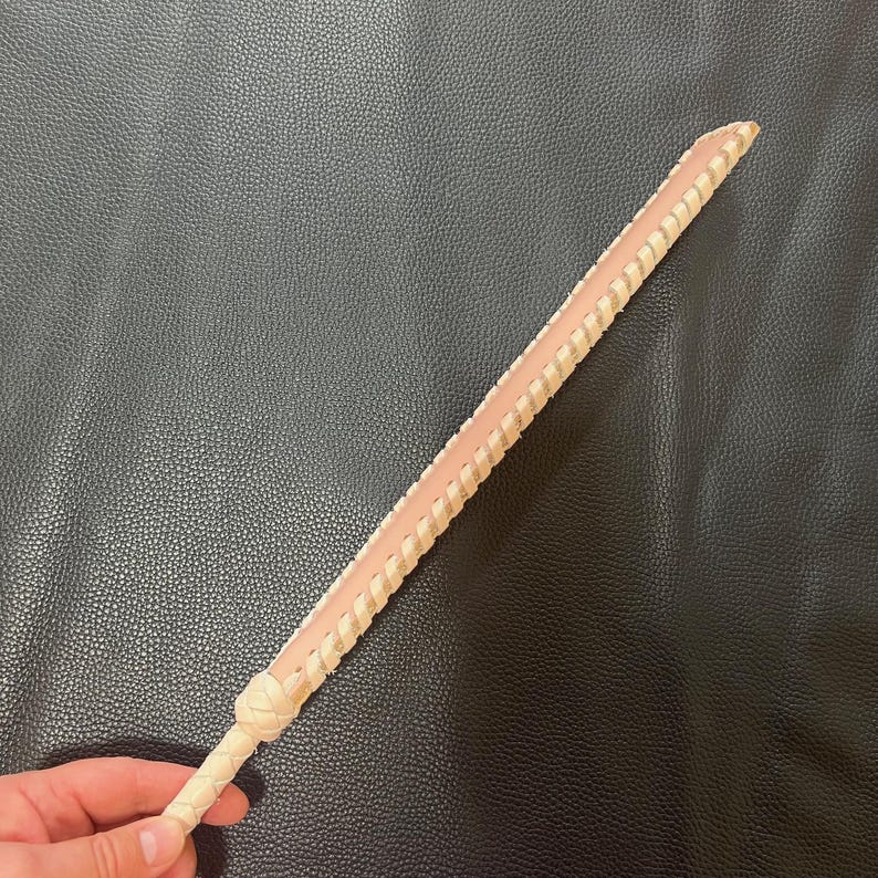 May include: A long, thin, braided leather whip with a light brown color and a pink undertone.